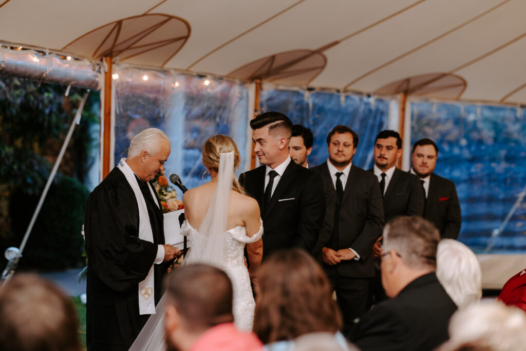 Bride and groom look towards their officiant at their rainy fall wedding ceremony at The Willowdale Estate.