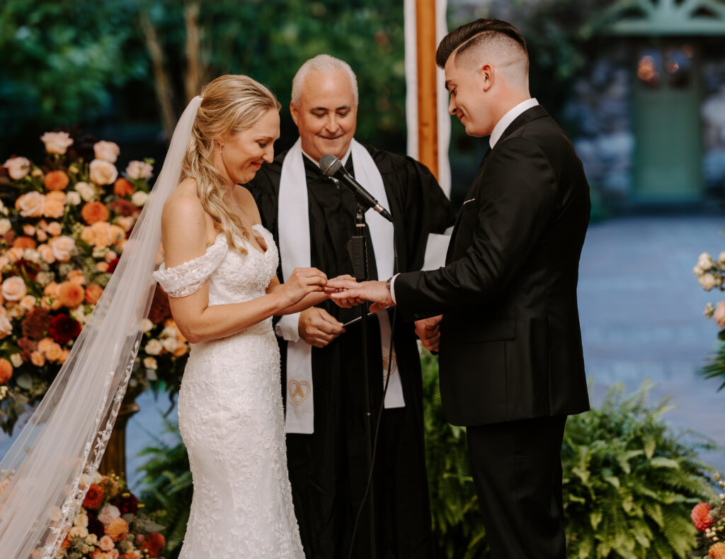 Bride and groom exchange wedding rings at their tented wedding ceremony at The Willowdale Estate.