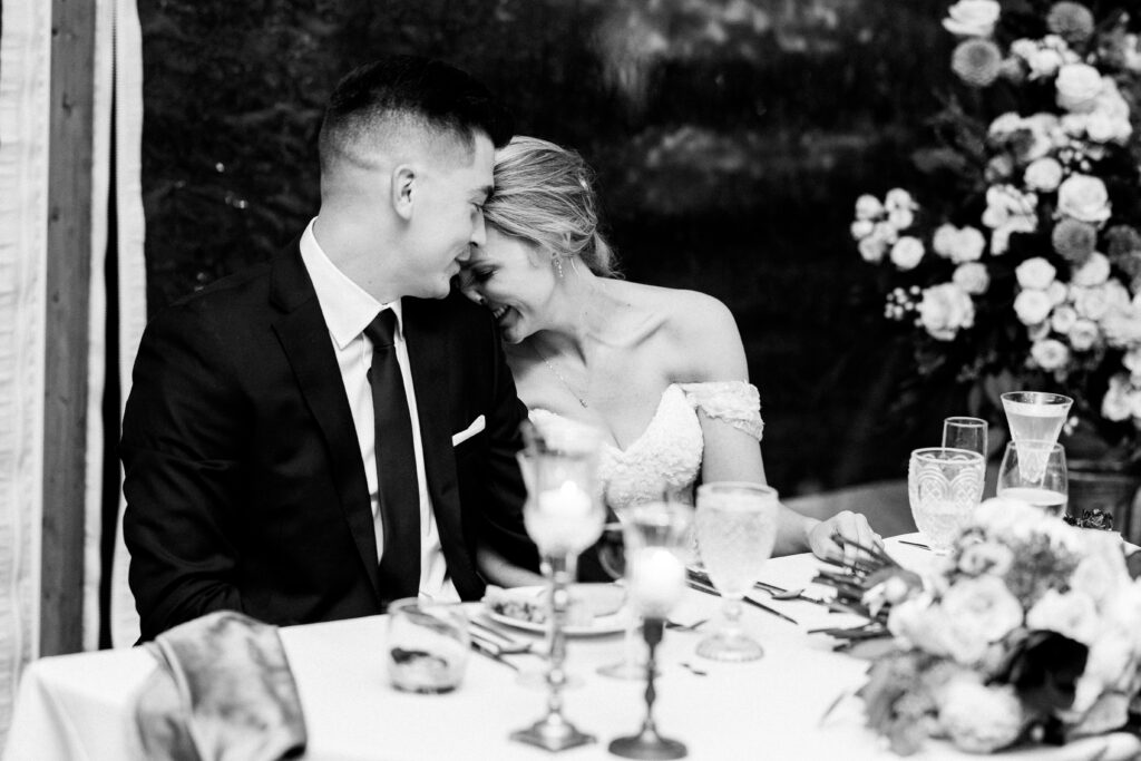Bride and groom nuzzle and laugh during toasts at their rainy fall wedding at The Willowdale Estate.