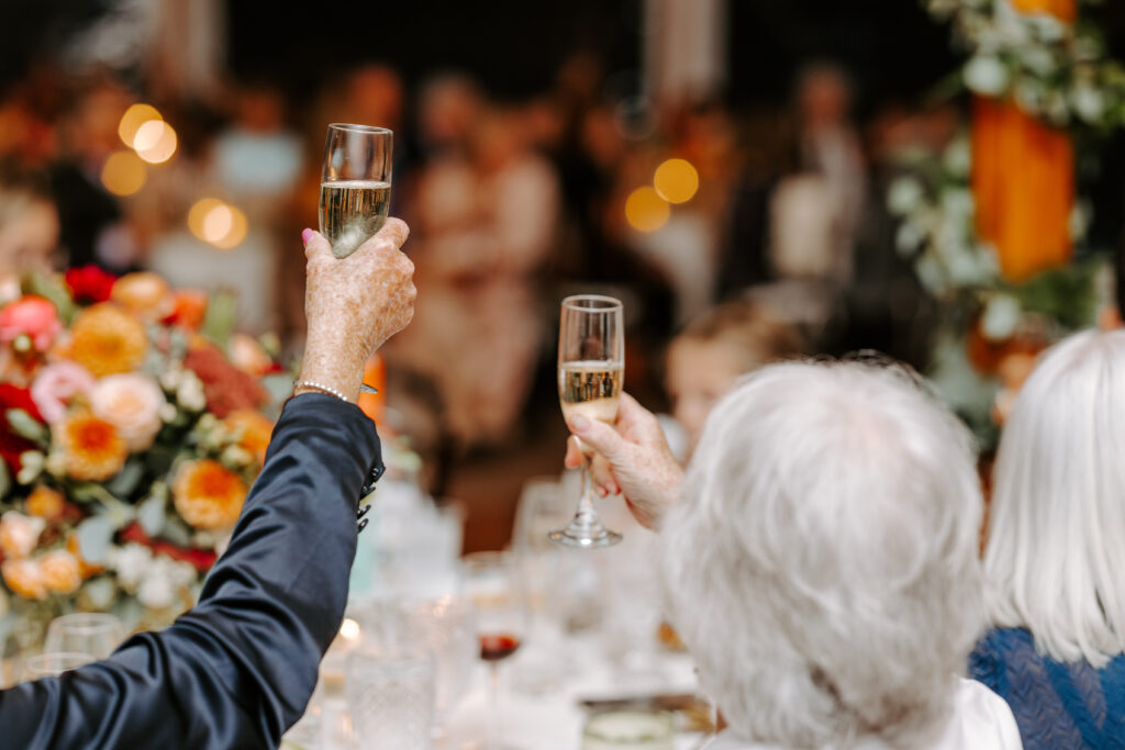 Two wedding guests share a toast at fall wedding reception at The Willowdale Estate.