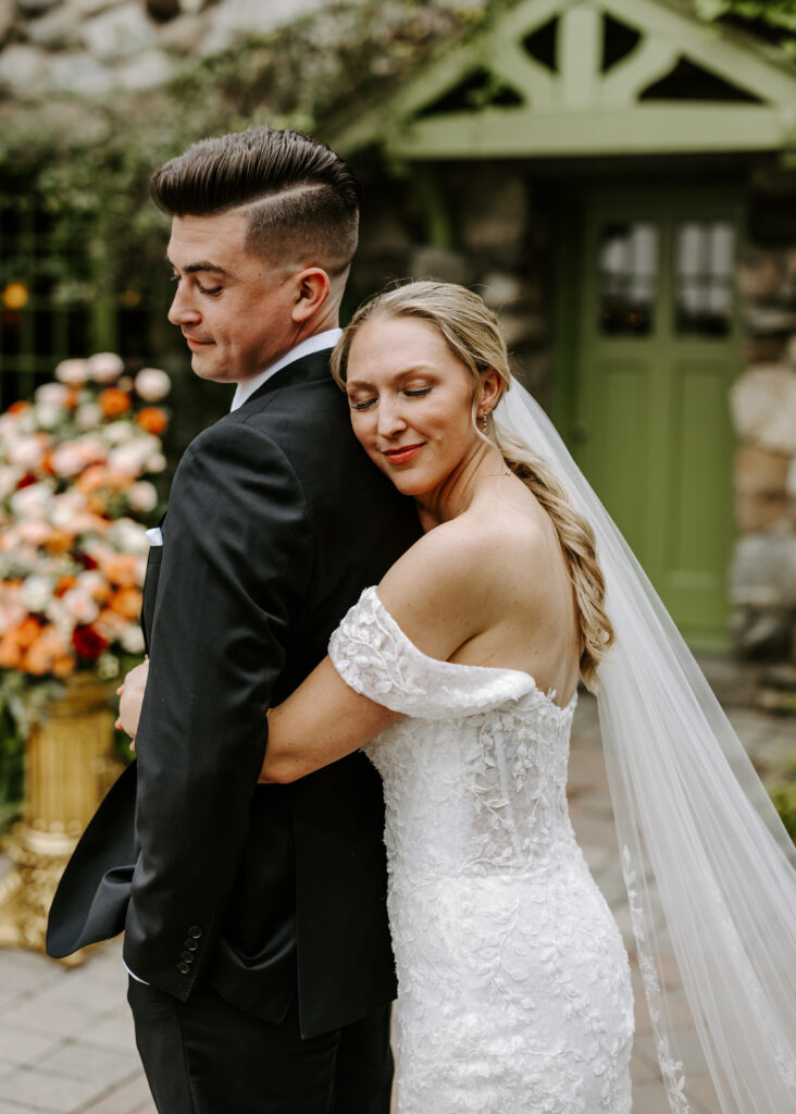 Bride hugs groom from behind and smiles as they take portraits for their wedding at The Willowdale Estate.