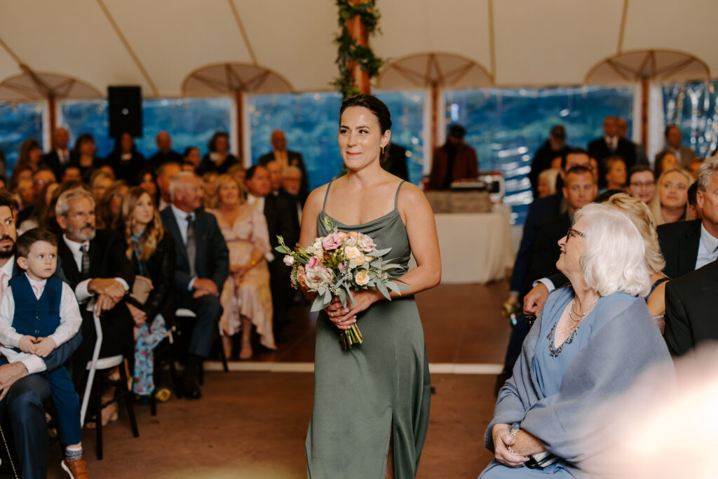 Bridesmaid walks down the aisle ahead of bride at a rainy fall wedding at The Willowdale Estate.