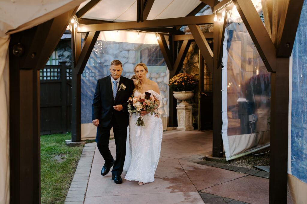 Bride and her father begin to walk down the aisle during her rainy wedding day at The Willowdale Estate in Topsfield, MA.