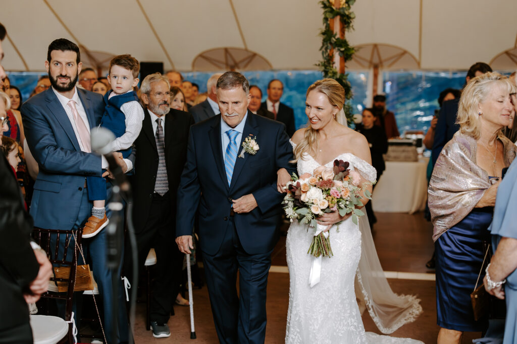 Bride and her father begin to walk down the aisle during her rainy wedding day at The Willowdale Estate in Topsfield, MA.