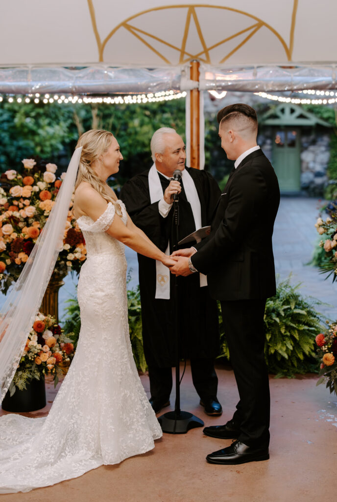 Bride and groom hold hands and look at each other during their wedding ceremony at The Willowdale Estate in Topsfield, MA.