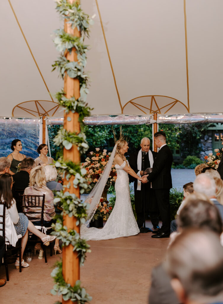 Bride and groom hold hands during tented ceremony at The Willowdale Estate in Topsfield, Massachusetts
