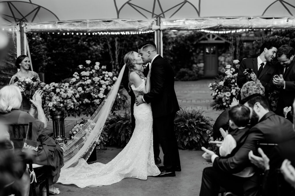 Bride and groom share their first kiss as husband and wife during their rainy wedding ceremony at The Willowdale Estate in black and white