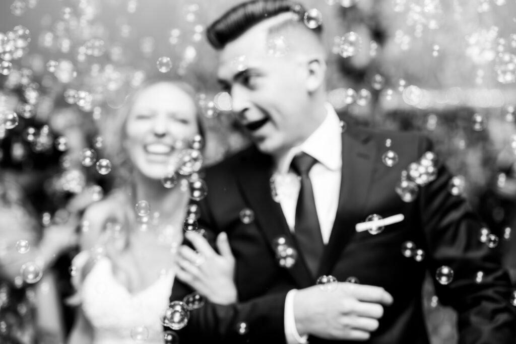 Bride and groom exit their wedding ceremony while bubbles surround them at The Willowdale Estate in Topsfield, Massachusetts.