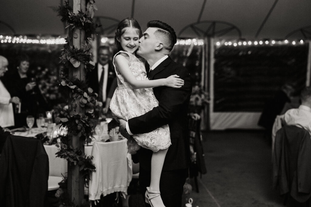 Groom picks up and kisses his niece on the cheek during his wedding reception at his fall wedding at The Willowdale Estate.
