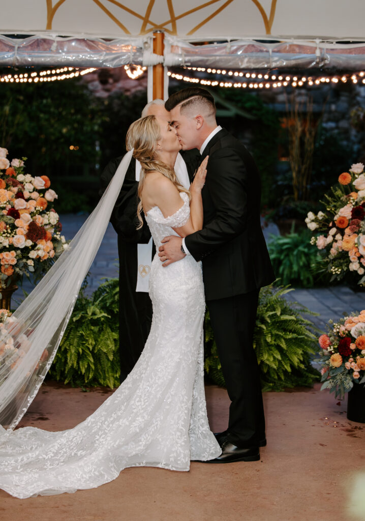 Bride and groom share their first kiss as husband and wife during their rainy wedding ceremony at The Willowdale Estate.