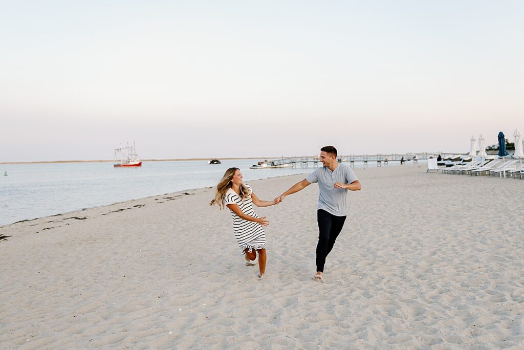 Bride and groom hold hands and run on the beach after Cape Cod proposal
