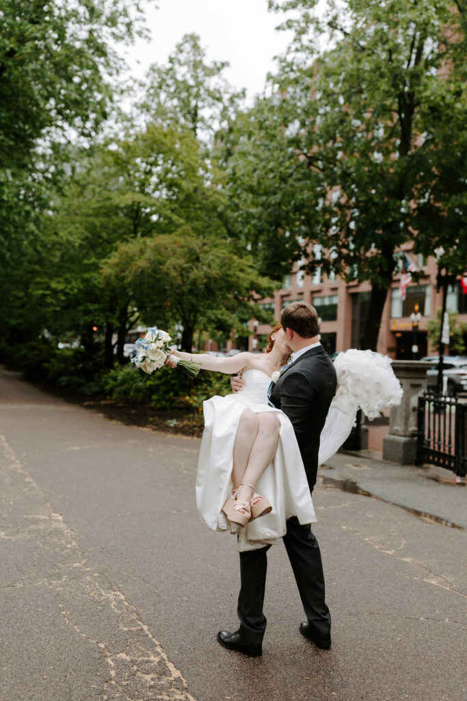 Groom holds bride and kisses her in Boston Commons