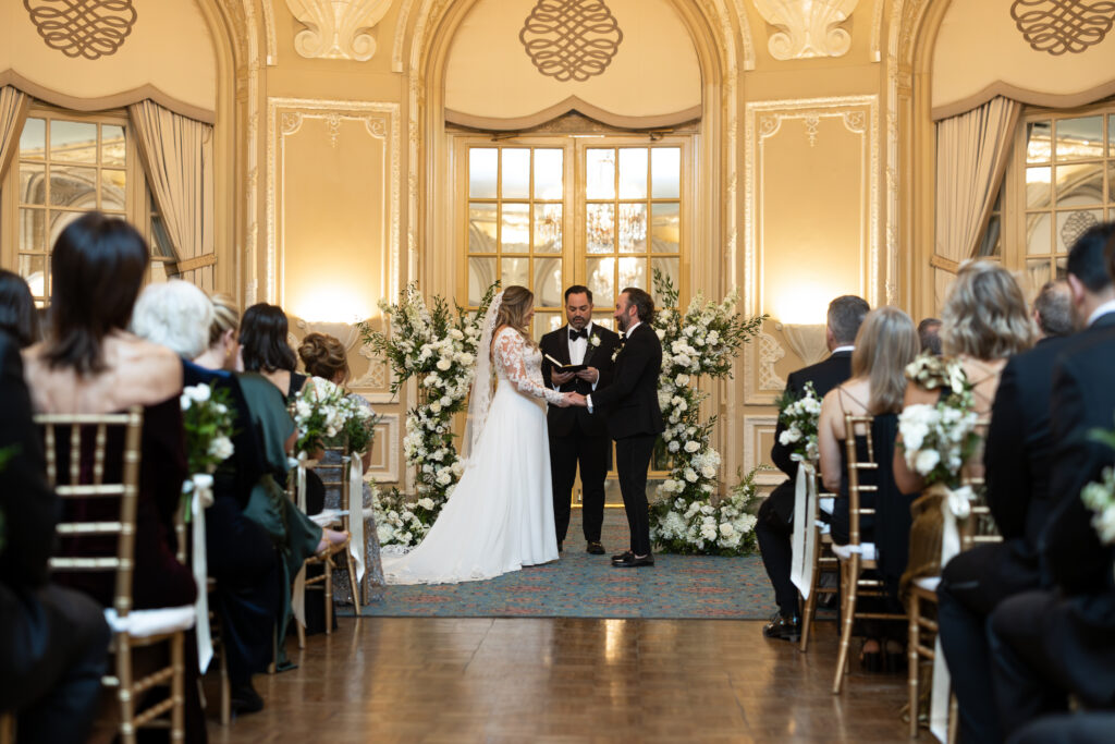 Bride and groom hold hands during wedding ceremony at Fairmont Copley in Boston