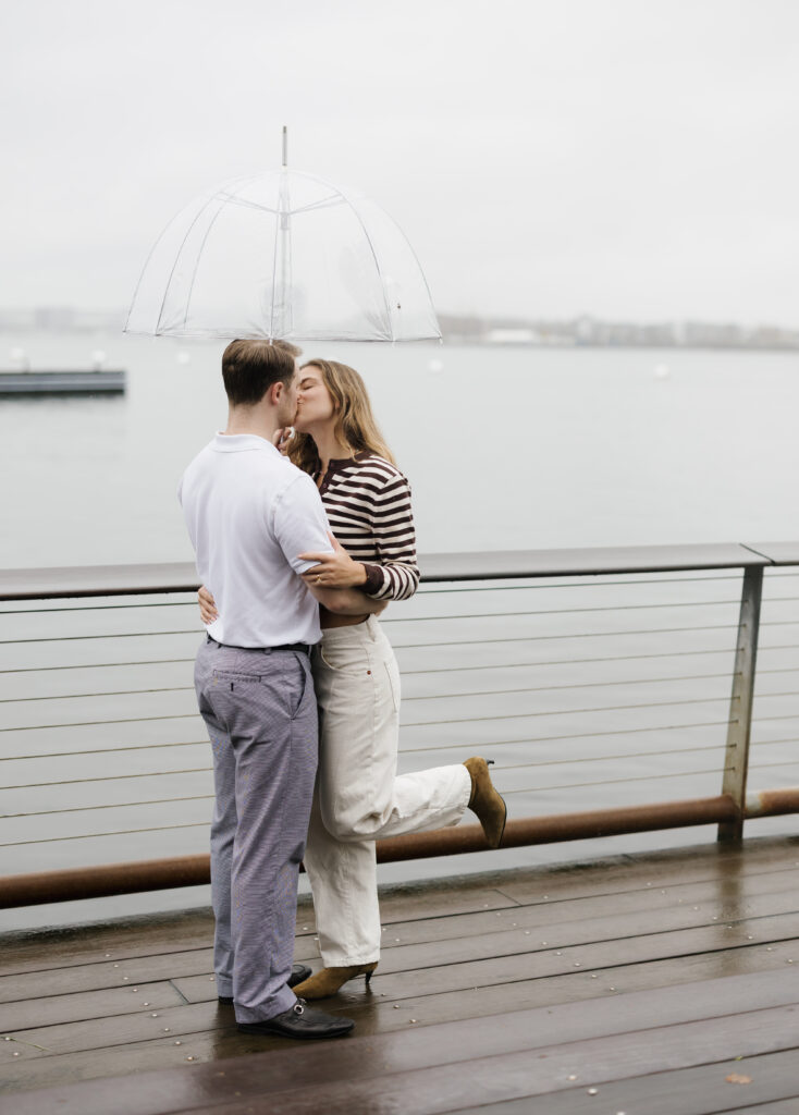 Couple kiss under clear umbrella after rainy proposal in boston