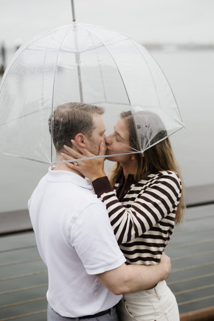 Couple kiss under clear umbrella after rainy proposal in boston