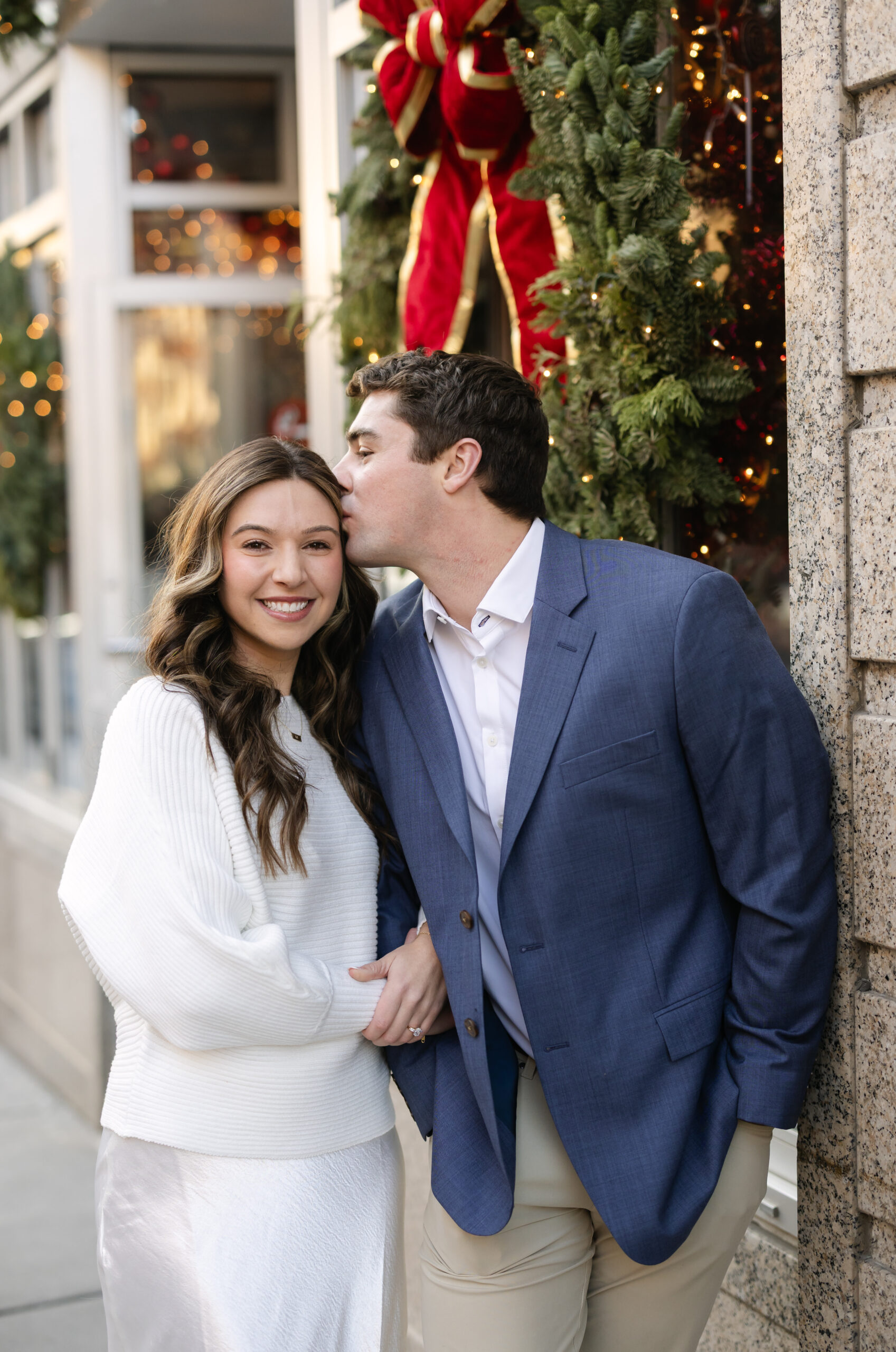 Groom kisses bride on cheek during engagement photos in Boston