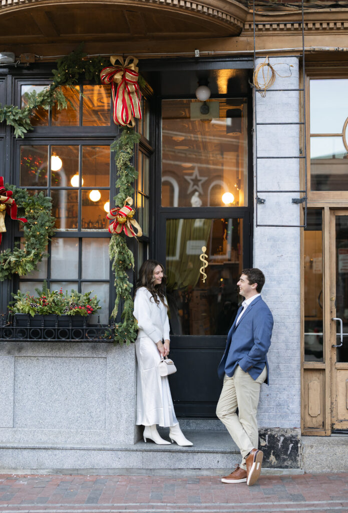Bride looks at groom at store front in Boston North End