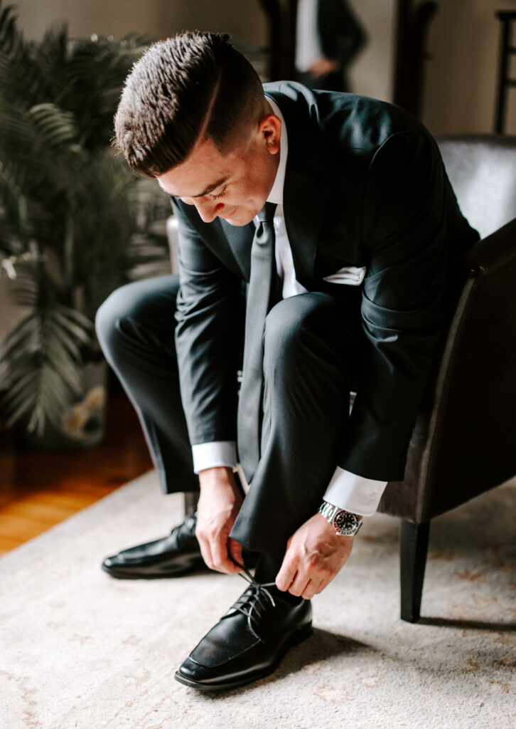 Groom ties his shoes as he gets ready for his wedding at The Willowdale Estate.