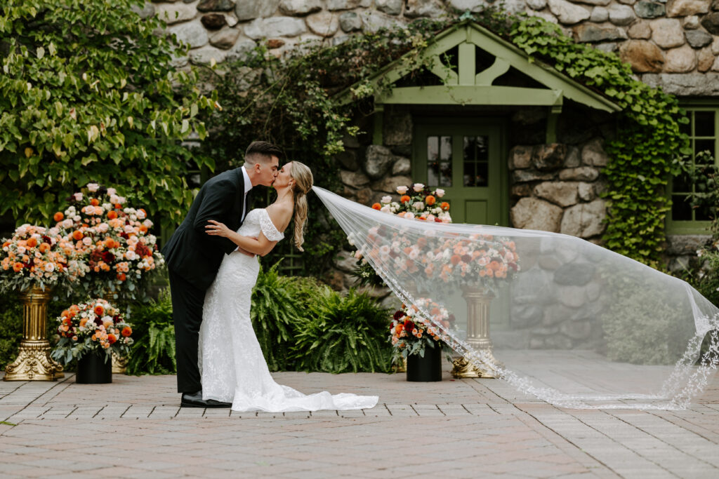 Groom dips bride back for a kiss and epic veil toss at their wedding at The Willowdale Estate.