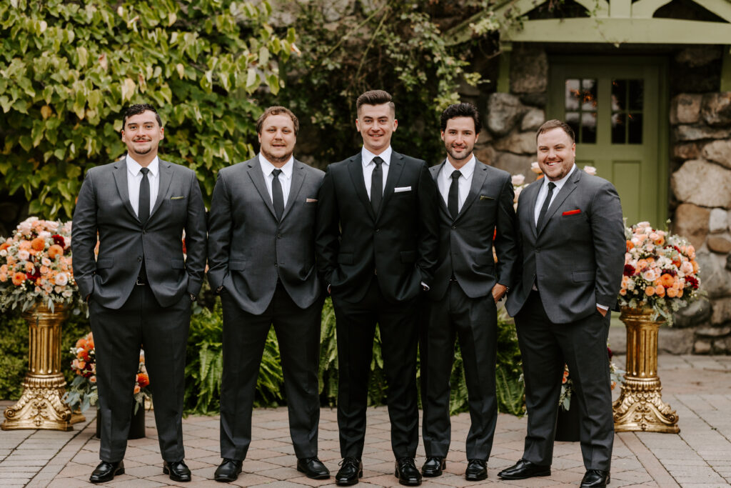 Groom and his 4 groomsmen (wedding party) smile in front of The Willowdale Estate before the wedding ceremony.