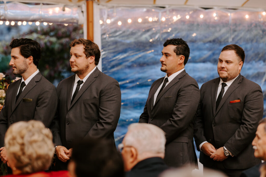 Groomsmen look towards the couple as they exchange their vows during their wedding ceremony.