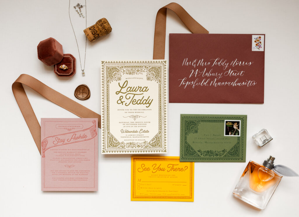 Wedding details and invitation suite including engagement ring, necklace, earrings, perfume.