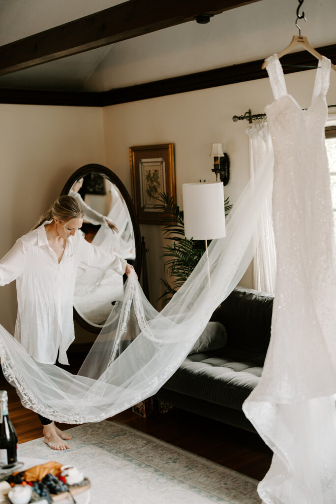 Bride steams her veil as wedding dress hangs in bridal suite at The Willowdale Estate for a fall wedding.