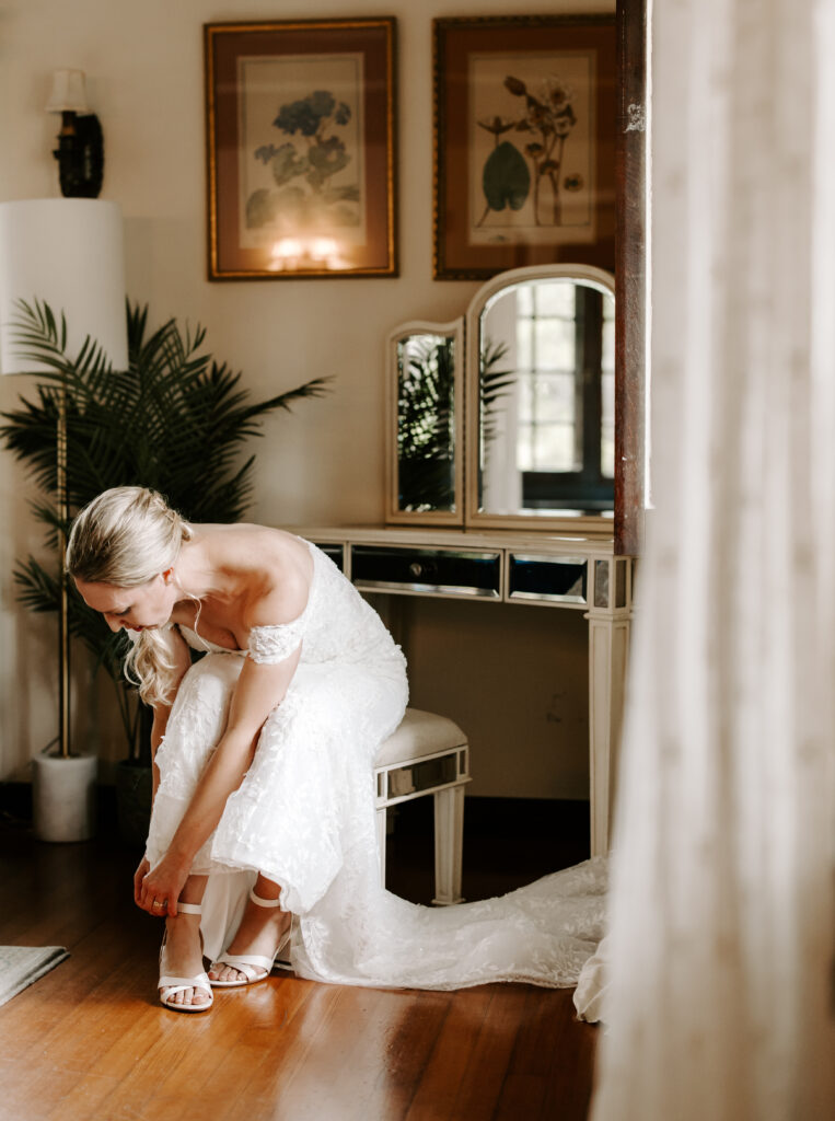 Bride puts on her shoes in the bridal suite for her wedding at The Willowdale Estate.