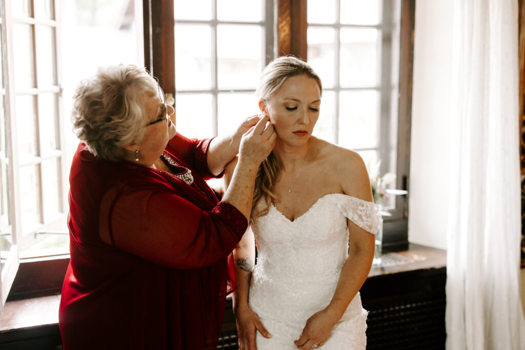 Bride's mother puts in bride's earrings as she gets ready for her wedding at The Willowdale Estate.