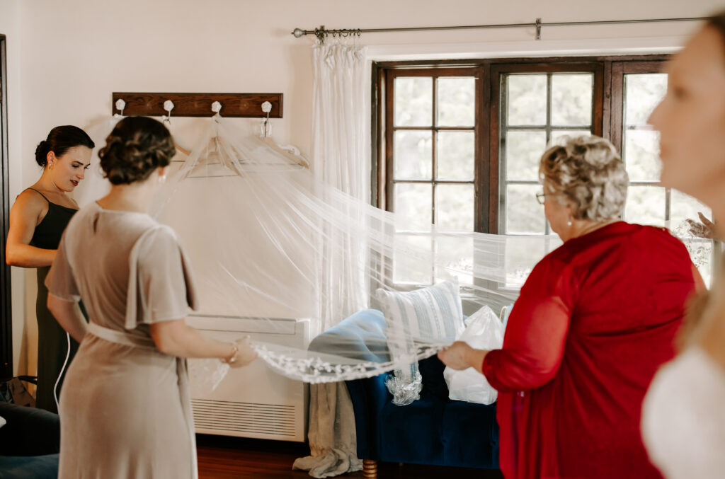 Bridesmaids and bride's mother steam the veil as bride gets ready for her wedding at The Willowdale Estate.