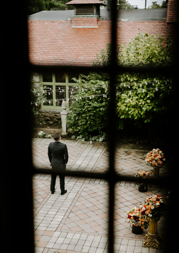 Groom awaits his bride in the courtyard for their first look at The Willowdale Estate.