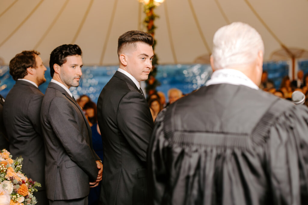 Groom looks over at officiant while he waits for his bride to walk down the aisle at their wedding at The Willowdale Estate.