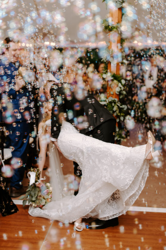 Bride and groom kiss while bubbles surround them during their tented wedding ceremony at The Willowdale Estate.