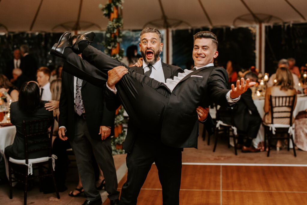 Wedding guests lifts up groom on the dance floor at The Willowdale Estate.