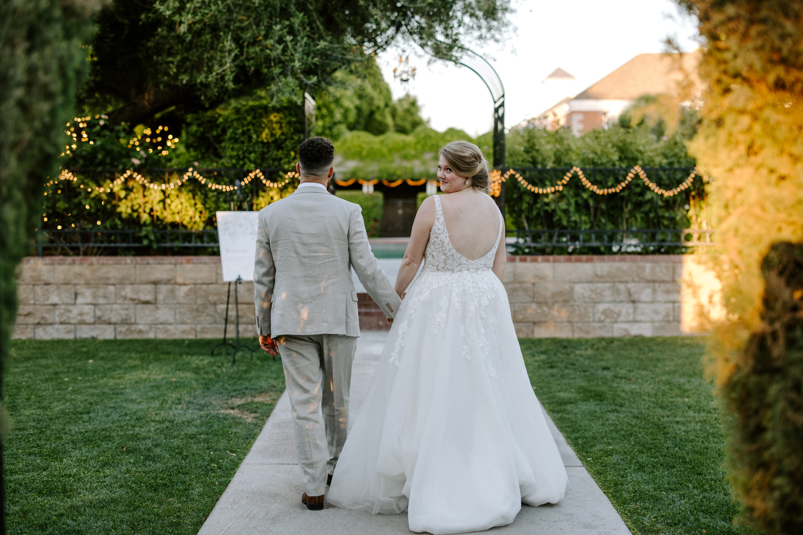 Bride and groom hold hands and walk away from wedding venue at May wedding at Stonebridge Manor Tempe, Arizona