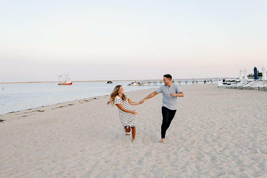 Bride and groom hold hands and run on the beach after Cape Cod proposal
