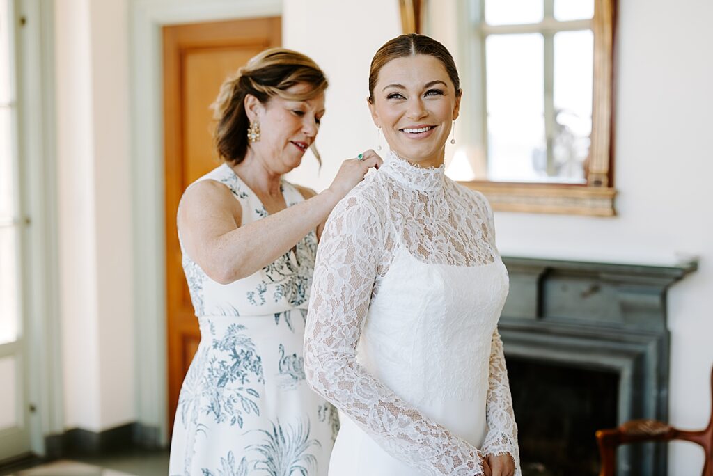 Mother of bride zips up bride's dress at Misselwood in Beverly, MA. Learn the essential wedding planning steps for newly engaged couples.