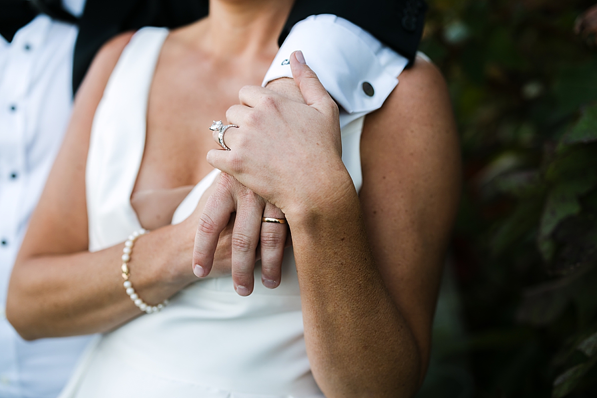 Groom puts arm around bride's shoulder to show off wedding ring. Learn the essential wedding planning steps for newly engaged couples.