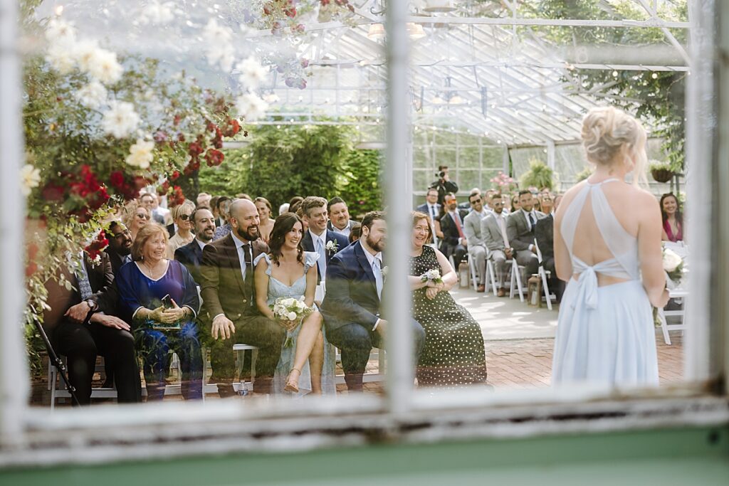 Greenhouse wedding ceremony, groom's family smiling at The Barn on The Pemi in Plymouth, New Hampshire.