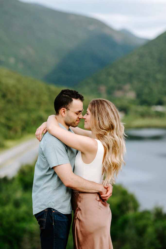 Bride and groom touch noses and smile in New Hampshire during summer mountain engagement photos in New Hampshire