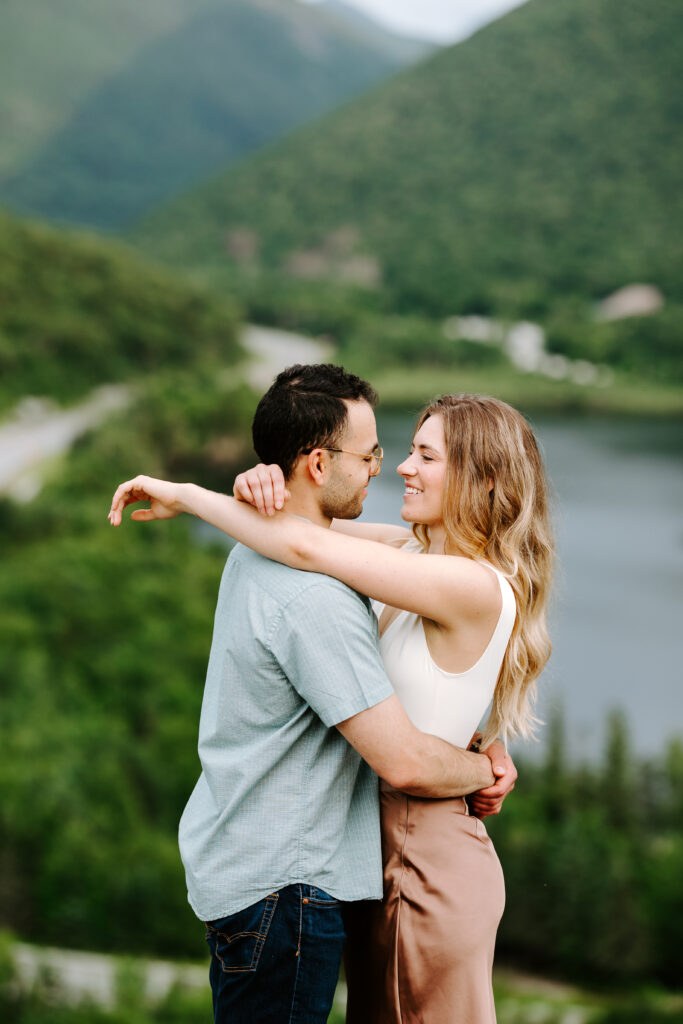 Bride and groom hold each other during engagement photo poses in summer mountain engagement photos in New Hampshire