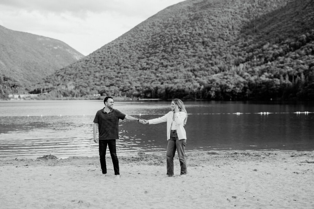 Soon to be married couple holds hands and looks towards each other in New Hampshire white mountains.