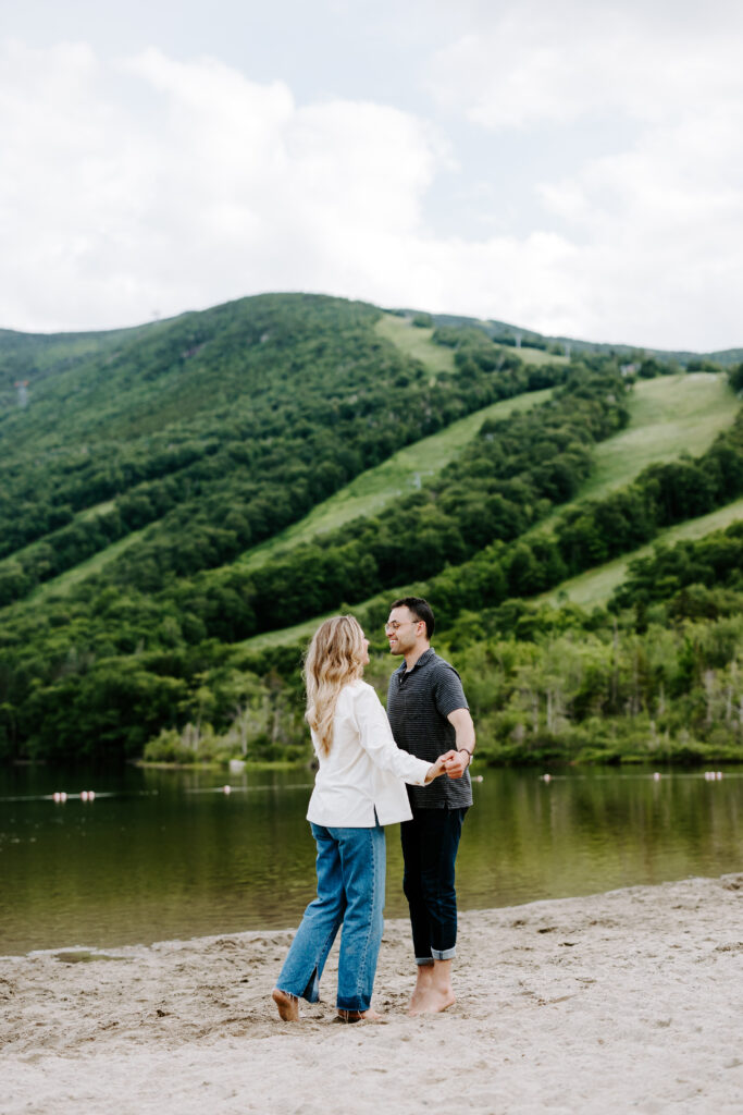 Bride and groom hold hands and smile at each other in New Hampshire white mountains engagement photos.