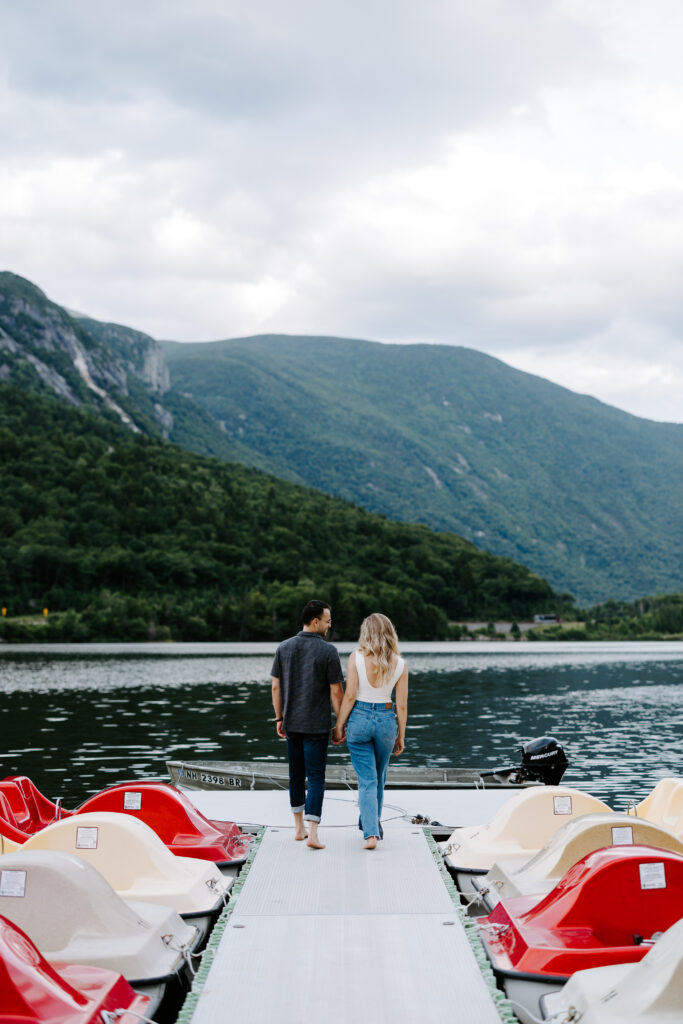 Bride and groom hold hands and walk away from the camera in New Hampshire white mountains with wedding photographer
