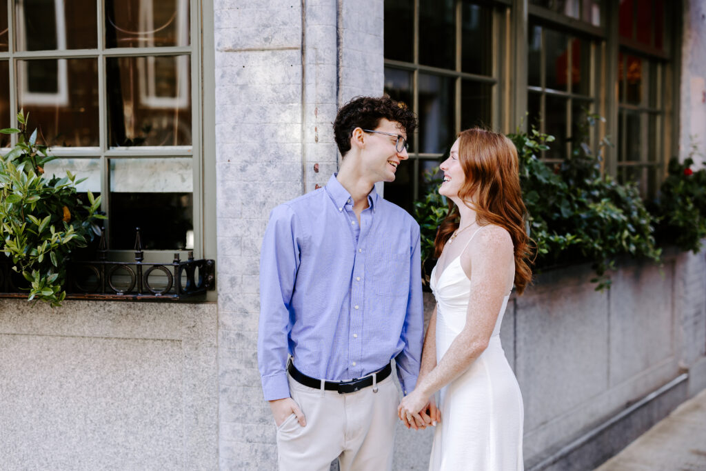 Couple laughs at each other during engagement session in boston