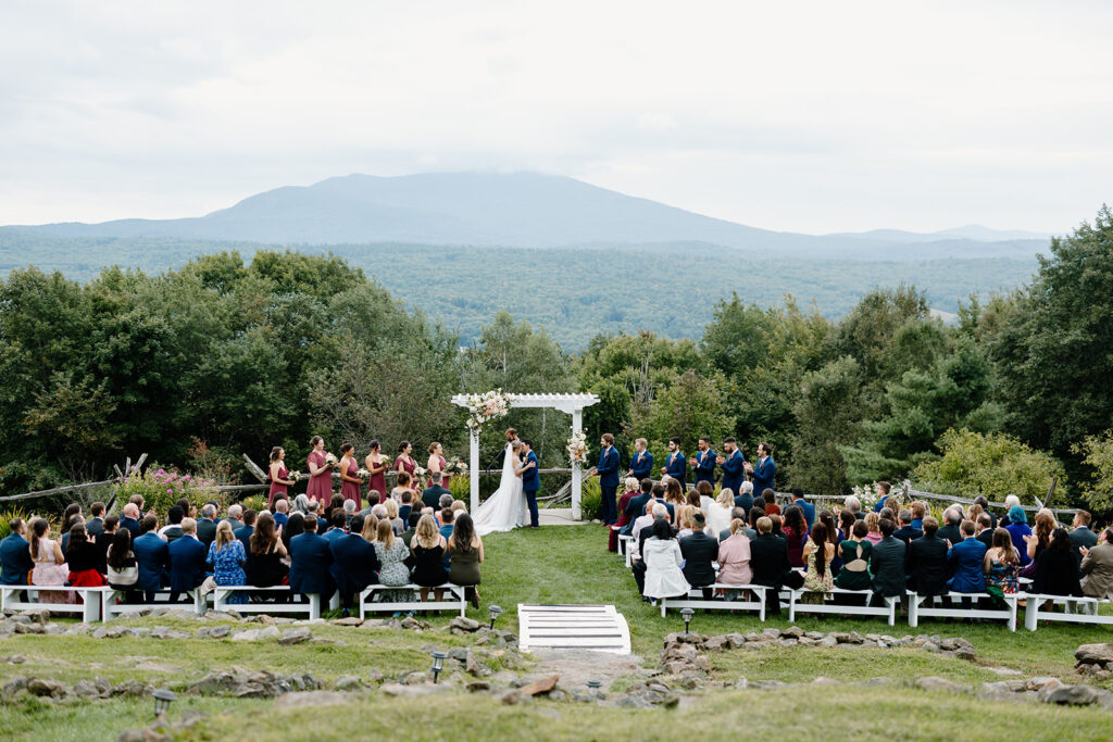 Bride and groom first kiss with new hampshire white mountains in the background at Cobb Hill Estate.