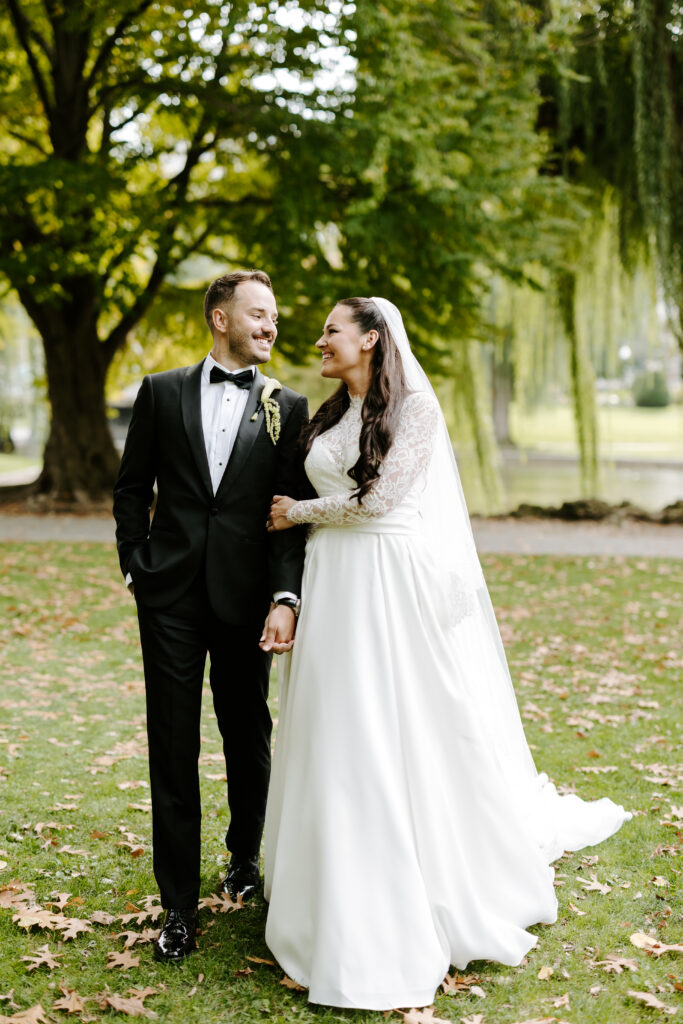 Couple walks hand and hand in Boston Commons on their fall wedding day at The Tower in Boston, Massachusetts.