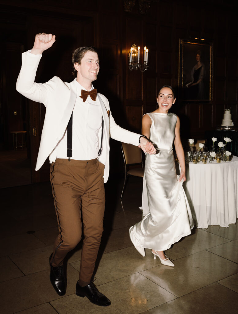 Bride and groom hold hands as they enter their wedding reception at The Boston Harvard Club in Massachusetts